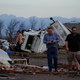 People walk through the ruins of downtown Mayfield, Kentucky, in the wake of a tornado. A Post Office deliver truck sits tossed on its side in the background.